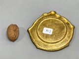 a gold plate with a nut on it next to a walnut