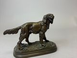 statue en bronze représentant un chien debout sur un socle, sur fond blanc