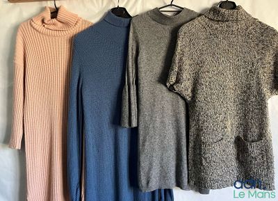three sweaters hanging on a clothes rack on a bed