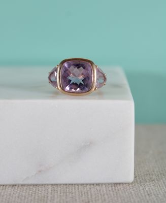 un gros plan d'une bague sertie d'une pierre violette posée sur un bloc de marbre