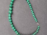 a close up of a green beaded necklace on a table