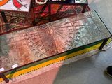une table en verre sur laquelle est posé un gâteau, avec une personne debout à côté