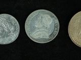 four different types of coins in a row on a black surface