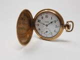 a gold pocket watch sitting on a white surface