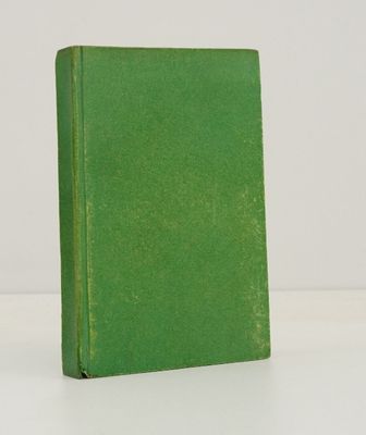 un vieux livre vert posé sur une table blanche