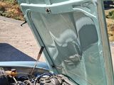 a green car with a hood open on the side of the road
