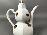 une théière blanche ornée d'un motif doré