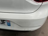 the rear end of a white car with a number plate on it