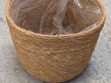 a wicker basket on the ground with a plastic bag in it