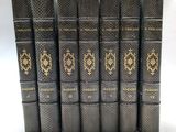 six vieux livres sont alignés sur une surface blanche