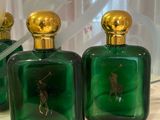 three green glass bottles with gold lids are on a shelf