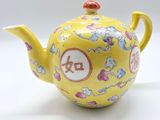 une théière jaune ornée d'un motif floral