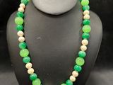 a green and white beaded necklace on a black mannequin