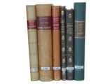 several old books are lined up on a shelf in a row