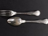 two silver spoons and a fork on a black surface