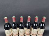 six bottles of red wine lined up in a row