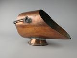 un petit objet en cuivre en forme d'oiseau posé sur un socle