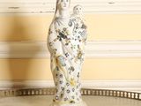 une figurine représentant une femme tenant un oiseau, posée sur une table