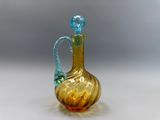 un vase en verre avec une anse bleue posé sur une table blanche
