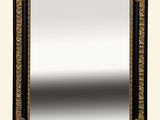 un miroir au cadre or et noir richement décoré, accroché à un mur blanc