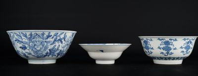 three blue and white porcelain bowls are lined up on a black surface