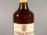 une image représentant une bouteille de vin de Château-Chalon posée sur une surface grise