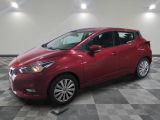 une Nissan Versa rouge garée sur un sol en carrelage à damier