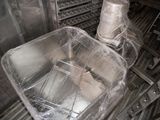 two pans that are wrapped in plastic on a conveyor belt