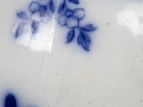 a close up of a blue and white vase with a bird on it