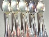 six silver spoons are lined up in a row on a table