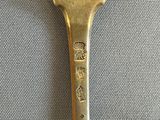 a silver spoon with a gold handle on a blue cloth