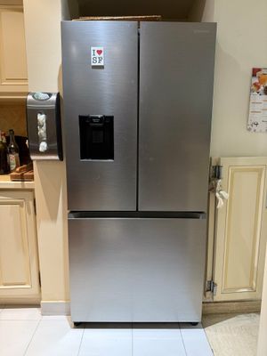 a stainless steel refrigerator in a kitchen with white tiles on the floor