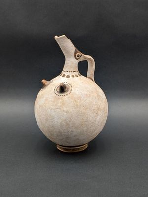 a white vase with a bird on it on a black background