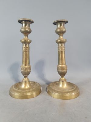 une paire de bougeoirs anciens en laiton posés sur un plateau de table en marbre