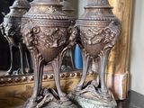 deux vases en argent posés sur une table devant un miroir