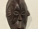 a wooden mask hanging on a wall on the wall