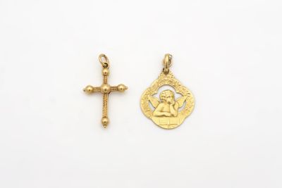 une petite croix en or et une petite médaille en or sur fond blanc