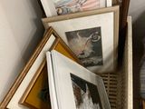 a pile of framed pictures on a shelf next to a bed