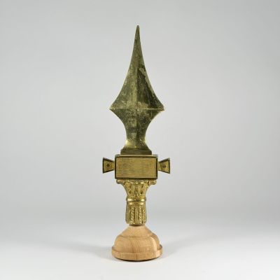 une image représentant un trophée en or au sommet pointu, posé sur un socle en bois