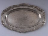 un plat en argent ancien posé sur une table blanche, sur fond blanc