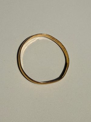 une bague en or posée sur une surface blanche, sur fond blanc
