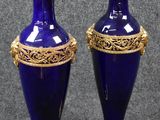 deux vases bleus ornés de touches dorées, posés sur une surface grise