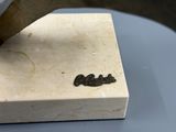 un petit objet métallique posé sur un bloc de marbre, dans lequel est enfoncé un couteau