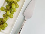 a white plate with grapes and a knife on it