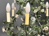 a chandelier with flowers and candles hanging from it