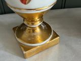 a white vase with a gold base on a table