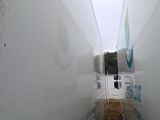 a man walking down a narrow hallway between two buildings