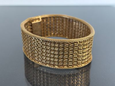 a close up of a gold bracelet on a black surface