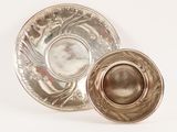 a silver plate and a silver cup on a white surface