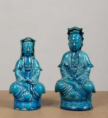 pair of blue glazed buddha figurines sitting on a table